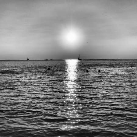 Anapa, Russia 23 August 2021 Sunset over the sea. Beautiful waves at sunset. Tourist mecca, resort. Evening sky. The rays are reflected from the water. Ships and people swimming in the seaのeditorial素材