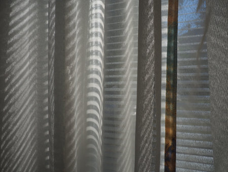 tulle and blinds on the windows. Light curtain transparent fabric with glare and rays of the sun....