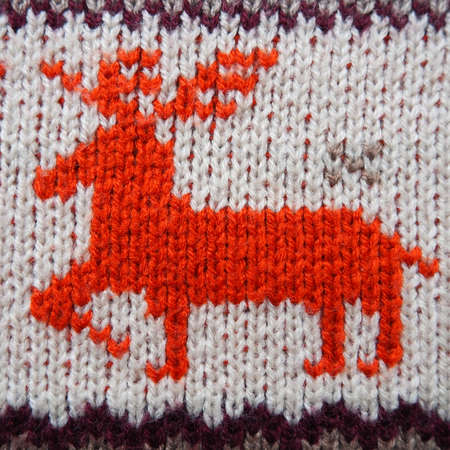 Jacquard knitted pattern. Geometric ornament for Christmas or New Year. Red deer on a white knitted background with horizontal zigzags. Winter fashionable modern animal traditional folk ornamentの写真素材