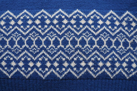 Jacquard knitted pattern. Knitted with white thread rhombuses and zigzags on a blue background. Geometric ornament for Christmas or New Year. Winter trendy modern traditional folk clothing ornamentの写真素材