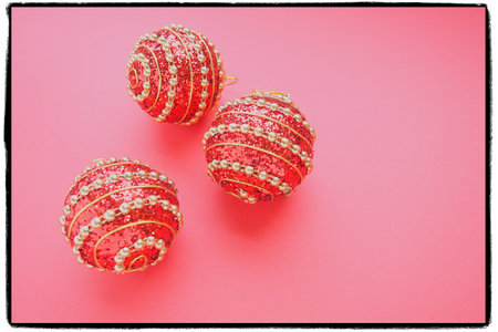Red large Christmas balls with gold stripes on a pink background. Three Christmas decorations. Merry Christmas, Happy New Year. Copy space and flat lay. Black and white frameの写真素材