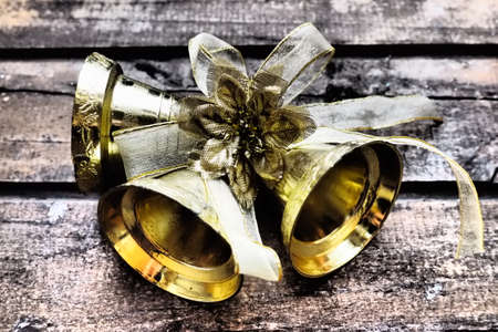 Gold bells with a bow on a wooden background. New Year and Christmas decorations. Retro vintage item.の写真素材