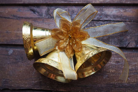 Gold bells with a bow on a wooden background. New Year and Christmas decorations. Retro vintage item.の写真素材
