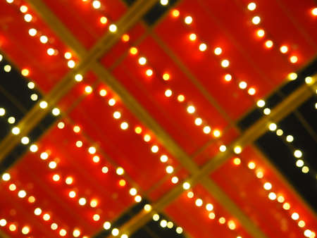 Bokeh on Christmas night. Beautiful round bokeh highlights. Red, yellow, gold, white colors in the dark. Festive background for New Year Merry Christmas. Blurred defocus. Decoration of city streetsの写真素材