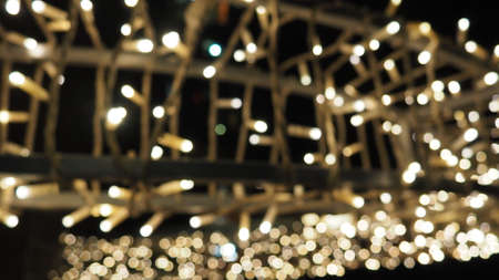 Street garlands with white small lamps in the evening on a city street. Festive new year christmas decoration city streets and parks.の写真素材