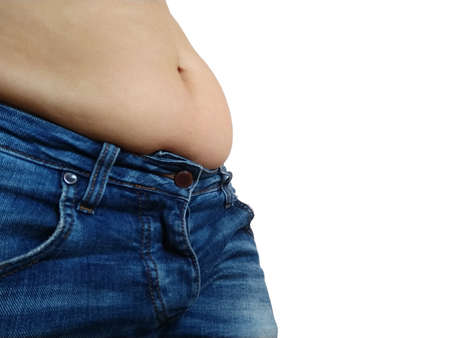 Saggy belly. Folds of leather and fat on the sides hanging over the waist of the jeans. A figure spoiled by overeating or pregnancy. Obesity and Diabetes. White background. Cellulite flabby musclesの写真素材