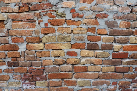 Brick wall of an ancient fortress. Uneven red and brown bricks with cement. Brick background.の写真素材
