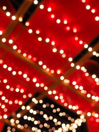 Bokeh on Christmas night. Beautiful round bokeh highlights. Red, yellow, gold, white colors in the dark. Festive background for New Year Merry Christmas. Blurred defocus. Decoration of city streets.の写真素材