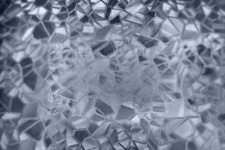 Embossed glass background. Corrugated glass monochrome. Refraction of light in a bumpy transparent surface under backlight. The play of white and gray highlights. Black areas. Abstract background.の写真素材