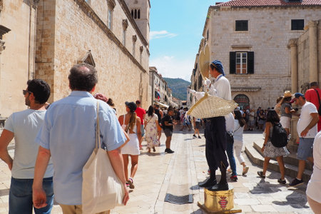 On the streets of Dubrovnik Croatia, happy vacationers walk and buy souvenirs from the seller in the national festive Croatian costume on August 15, 2022. Tourism industry. Summer day. Sale of goodsのeditorial素材