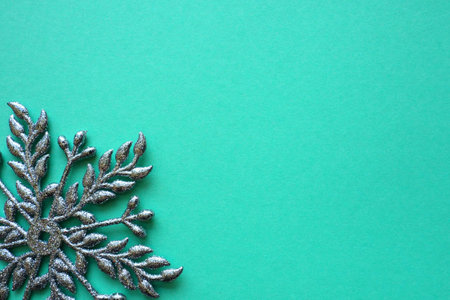 New Year or Christmas background with decorative snowflake around the edges of a sheet of colored paper. Copy space. Blue silver snowflake on a green background. Postcard, background or invitation.の写真素材