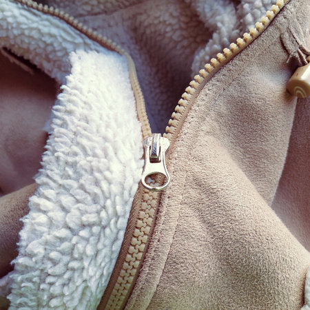Suede outerwear. Overhead loops for buttons. Open zipper. Beige faux suede with sheepskin on the fold of a demi-season garment. seams in the material. Clothing industry and fashion.の写真素材