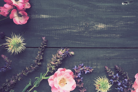 Flowers in a semicircle on a wooden background. Postcard for the holiday. Roses, lavender, sage and hairy chestnuts along the edges on dark boards. Background copy space, flat lay. Festive poster.の写真素材