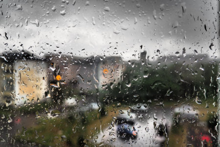 bad weather in the city. Buildings, houses, cars outside the window. Cloudiness cumulus clouds. Meteorology and weather forecast. Raindrops run down the glass. Storm and Storm and wind on city street.の写真素材