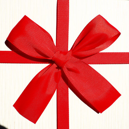 White gift box with red ribbon bow isolated on white background