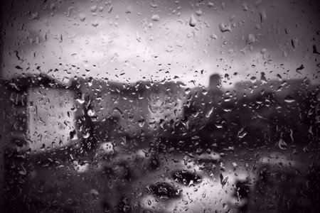 bad weather in the city. Buildings, houses, cars outside the window. Cloudiness cumulus clouds. Meteorology and weather forecast. Raindrops run down the glass. Storm and Storm and wind on city street.の写真素材