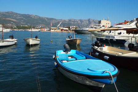 Budva, Montenegro, August 15 2022 Adriatic sea, coast, mountains, sea ripples. Boats and ships are moored to the embankment. Water transport parking. Summer resort trips with water activities. Tourismのeditorial素材