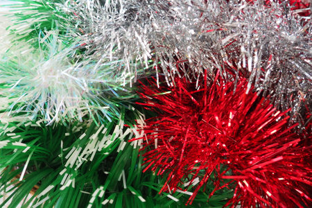 Multi-colored Christmas tinsel. Red, green, silver and white tinsel are intertwined. Festive New Year or Christmas background. Christmas decorations. Decoration of the hall for a party. Christmas boaの写真素材