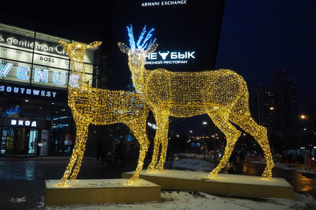 Moscow, Russia, January 17 2023 Metro Yugo-Zapadnaya. Christmas decorations in front of the mall. New year street decorations in the form of sparkling deer. Deer figure made from yellow gold garlands.のeditorial素材