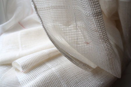 White coarse cotton or linen curtains made of weaves of thin threads. Simple compact economical...