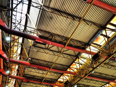 The roof of a hangar, a production hall or a sports hall. Metal structures, beams, supporting elements. Ventilation systems in large halls and rooms. Skylights. Industrial interior.の写真素材