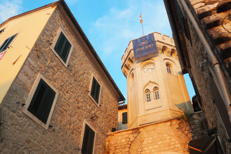 Herceg Novi, Montenegro, 08.10.2022 Sahat Kula, a clock tower, passage between two squares. It is a popular tourist attraction. The flag of Herceg Novi flutters in the sun and wind. Sunset golden hour.のeditorial素材