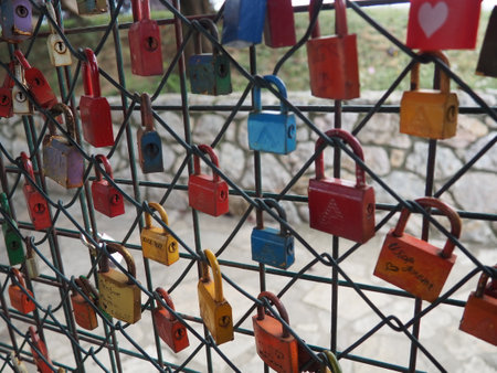 Stanisici Bijelina Bosnia and Herzegovina 08.15.2023 Buttoned multi-colored metal locks on a lattice or bridge as a symbol of love and fidelity. wedding tradition. Watermill wall. Tourist attractions.のeditorial素材
