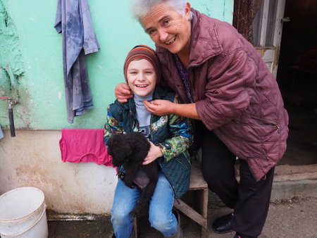Happy grandmother and grandson. Black dog in the arms. The family is laughing and having fun. An elderly woman hugs a boy of 8 years old. People communicate outdoors. 7 February 2021 Belgrade Serbiaのeditorial素材
