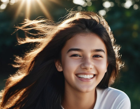 A portrait of young woman with long brown hair, smiling brightly. The sun shines on her face, highlighting her white teeth and happy expression. Brown eyes, dark skin, tousled dark hair. AI generated.の素材