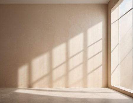 Beige wall and large window. Sunlight is streaming through window, casting long shadows on wall. Room is bright and airy, with clean, minimalist feel. Background for interior or product display.の素材