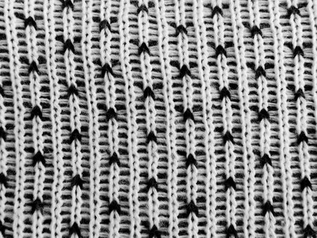 Detailed view of a winter knitting pattern showcasing delicate black stitches against a soft white fabric, perfect for creating warm, stylish accessories during chilly months.の写真素材