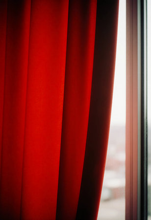 Thick, vibrant red curtains hang near a window, allowing soft light to stream into the space. The fabric adds warmth and color to the room, creating a cozy atmosphere.の素材