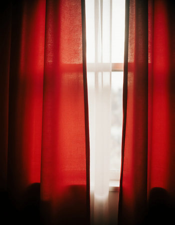 Sunlight streams through translucent red curtains, creating a warm and welcoming ambiance in a room. The soft fabric adds color and charm, illuminating the space softly.の素材