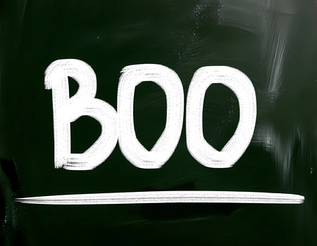 A chalkboard displays the word Boo in large white letters. It is October, and the Halloween spirit fills the classroom with decorations and excitement.の素材