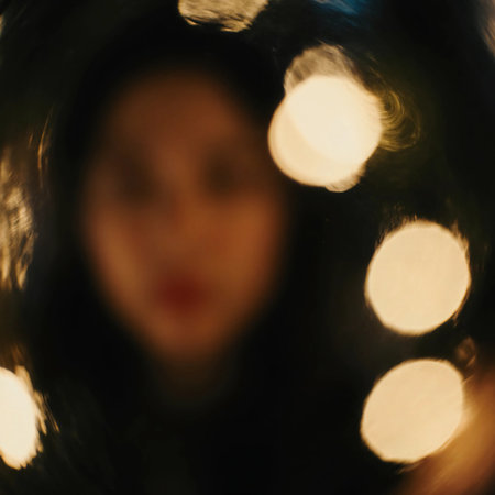 A woman stands in front of bright Christmas lights, her face blurred. The warm bokeh effects create a festive atmosphere, representing the holiday season and New Year spirit.の素材
