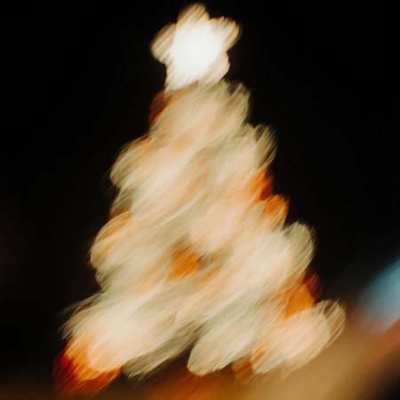 Bright lights and colors from a Christmas tree shine in the night. The decorations create a festive feel as the holiday season arrives. The blurred focus adds a special touch.の素材