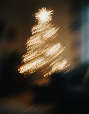 A Christmas tree is lit up with bright lights, creating a warm atmosphere. The image shows a blurred view, capturing festive spirit in a home during the holiday season.の素材