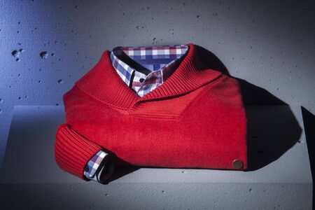 Folded red sweater and patterned, checked men's shirtの写真素材