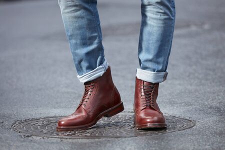 Young fashion man's legs in blue denim jeans and brown boots.の写真素材
