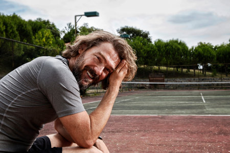 Handsome mature man sitting and laughing. Happy sporty man looking at camera and laughing in a...