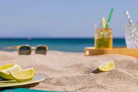 Slices of lime with sunglasses on the sand near the seaの写真素材