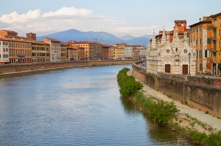 Church and buildings at river Arno in the city of Pisa の写真素材