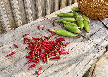 Fresh chili and corn on wooden table, food ingredients in rural China.の写真素材