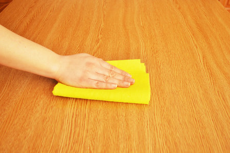woman cleaning furniture table with yellow cloth