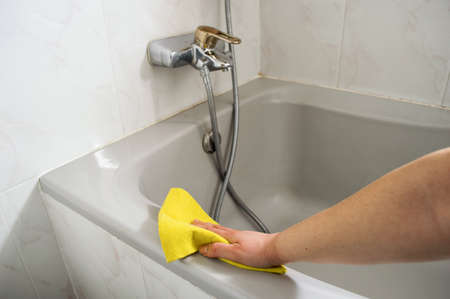 A woman cleans her Bathtub with yellow clothの写真素材