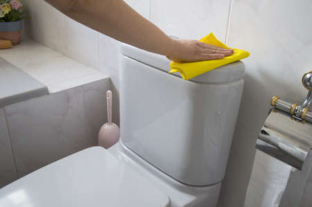 A woman cleans a toilet with yellow clothの写真素材