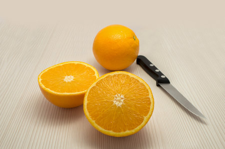 whole orange and one departure and a knife on the tableの写真素材