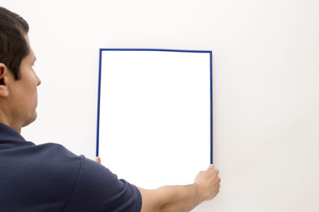man putting a picture on the wall