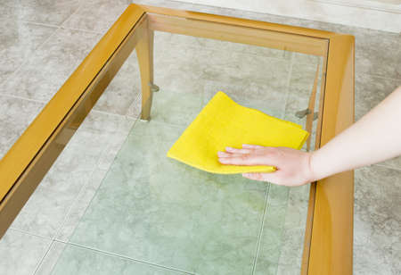 cleaning a glass table with yellow clothの写真素材