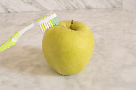 Apples with a toothbrush isolated on marbleの写真素材